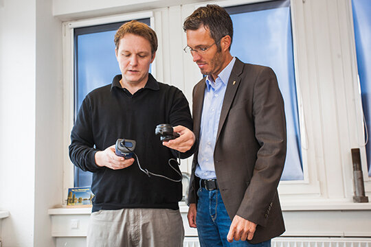 Foto: Zwei Mitarbeiter der Buhck Gruppe mit einem Meßgerät in der Hand, stehen in einem Büro